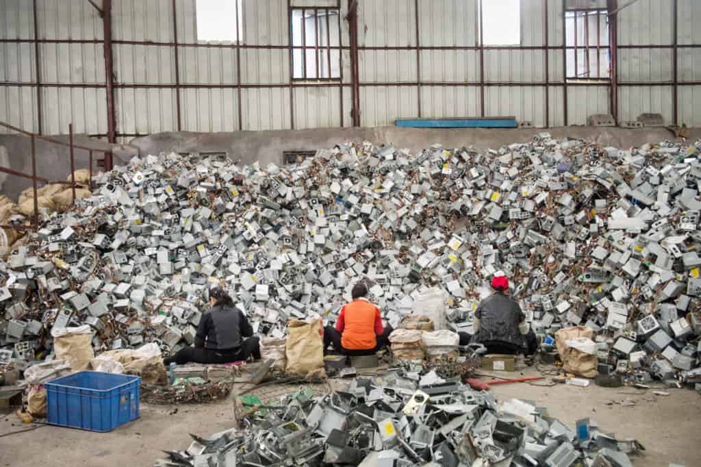 Arbeiter in China sortieren händisch ein Berg von E-Schrott in einer riesigen Halle.